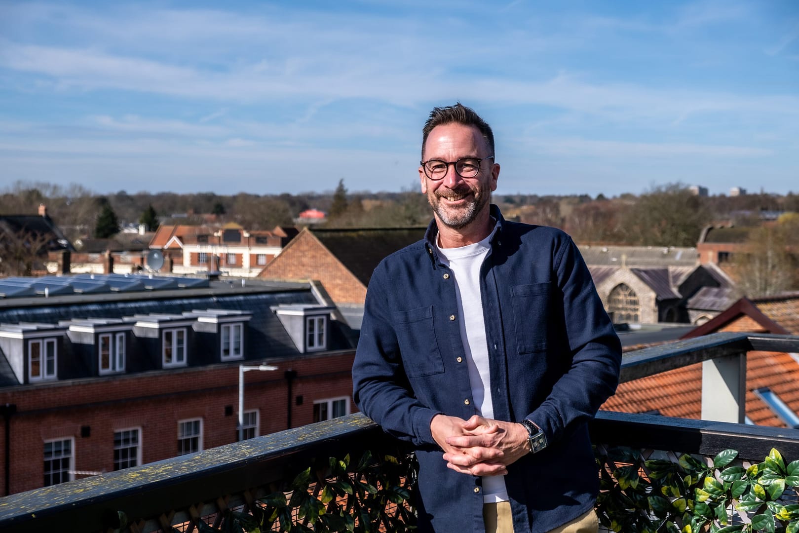 Man smiling on rooftop with town view
