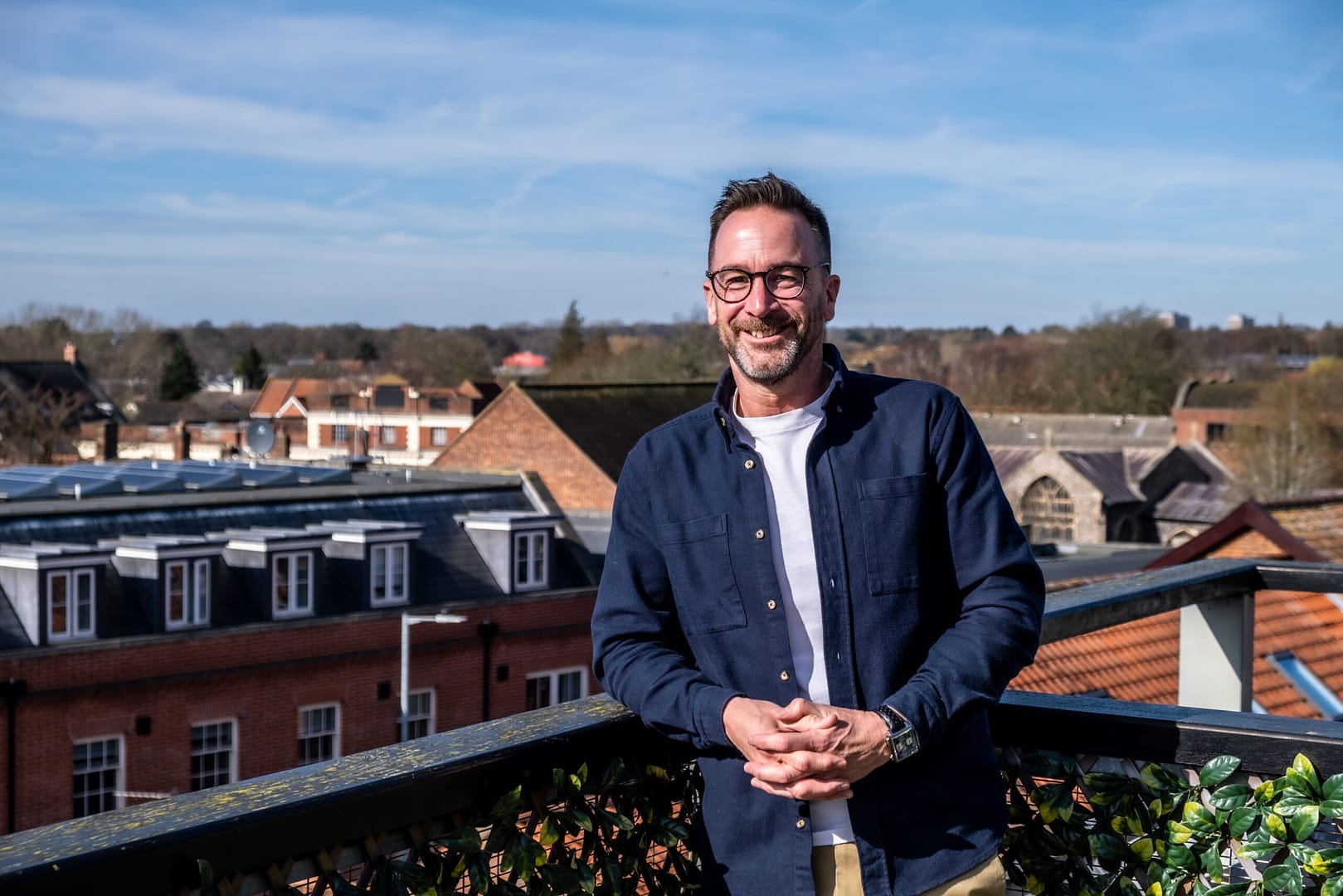 Man smiling on rooftop with town view