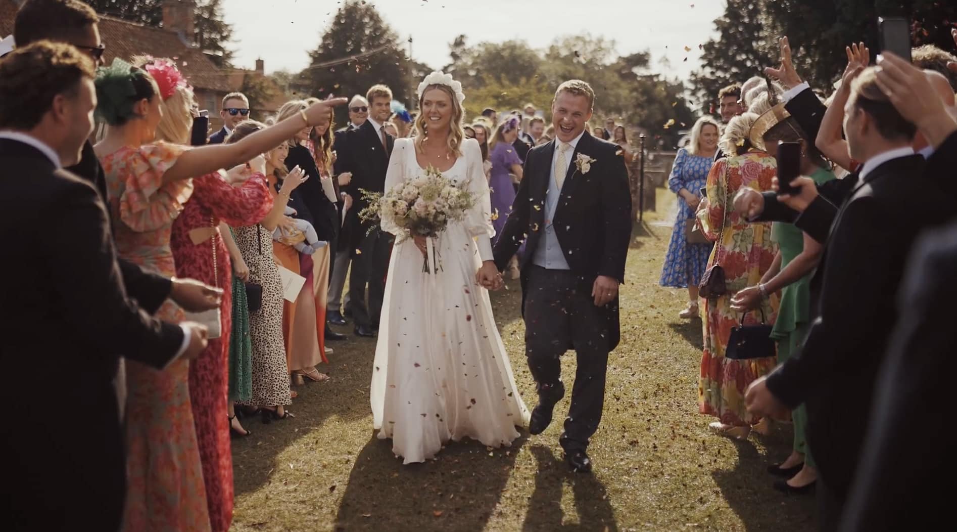 Wedding couple exits, guests celebrate with confetti.