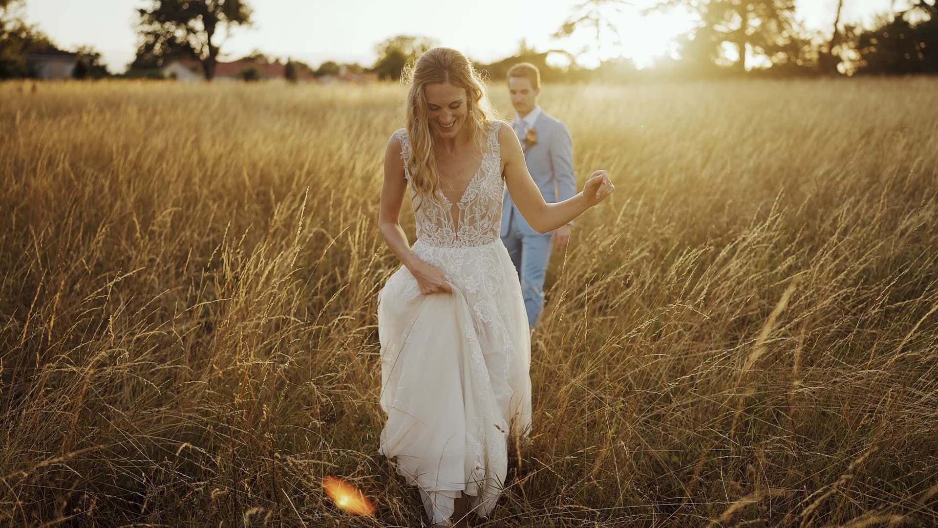 Bride and groom walking through sunny field