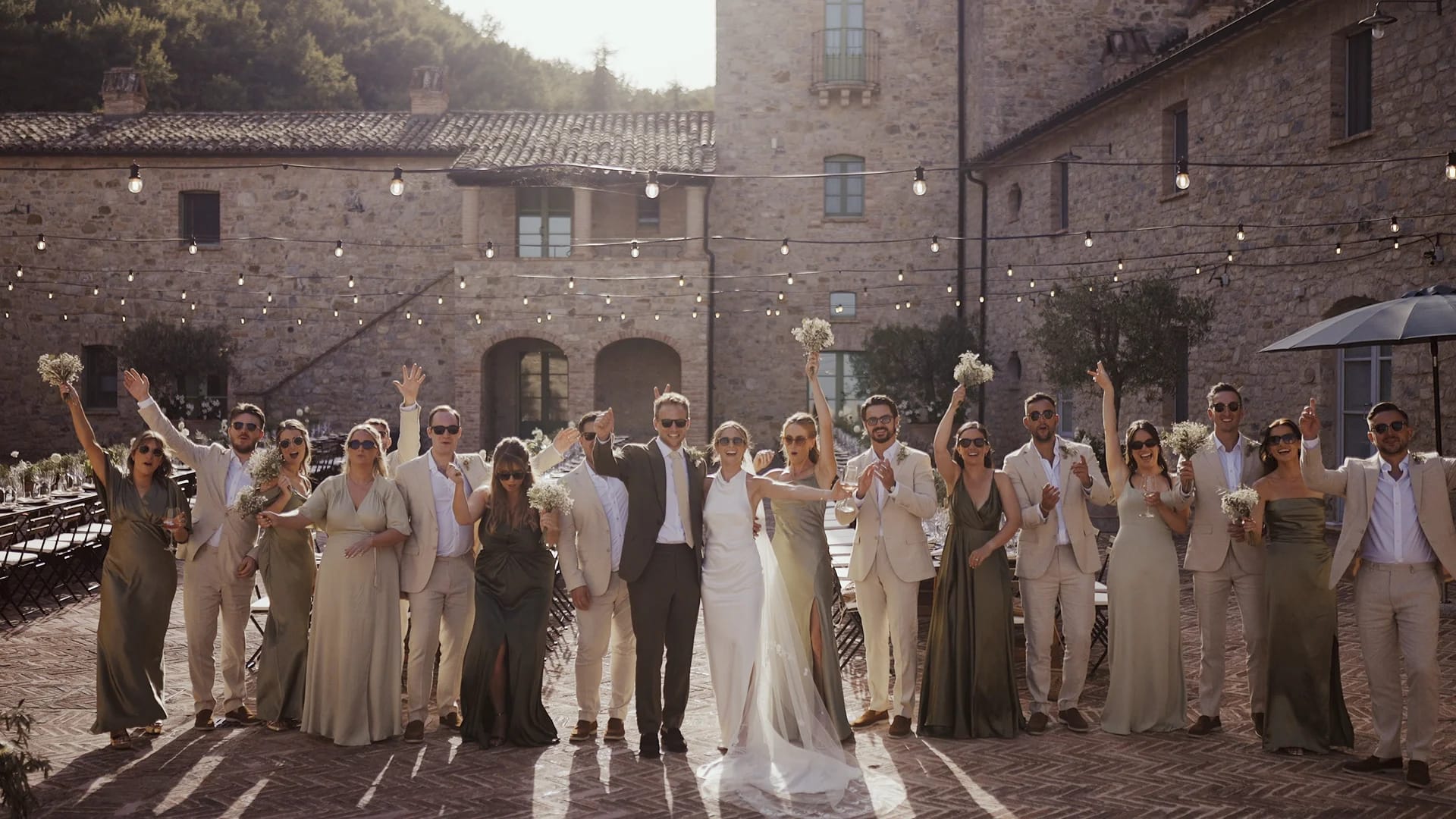 Wedding party celebrating outdoors with string lights.