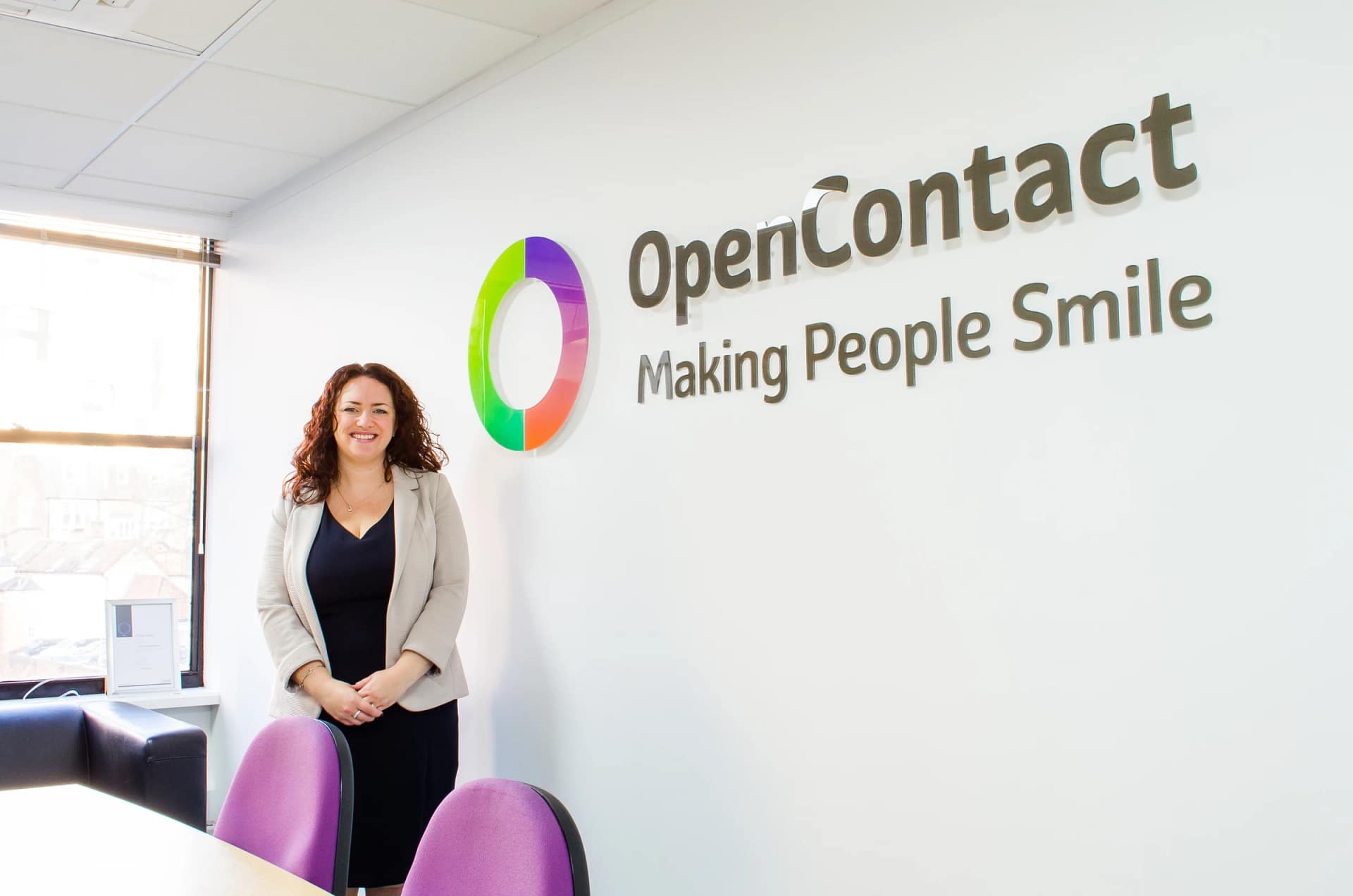 Businesswoman standing beside OpenContact office logo