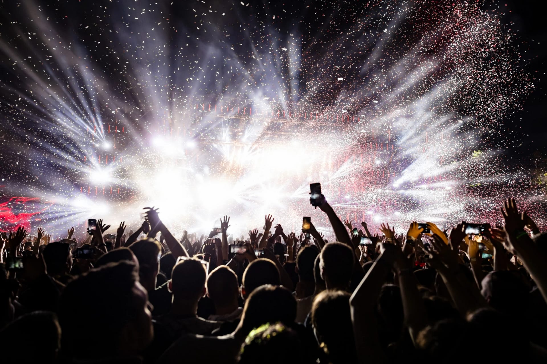 Excited crowd enjoying live concert with bright lights