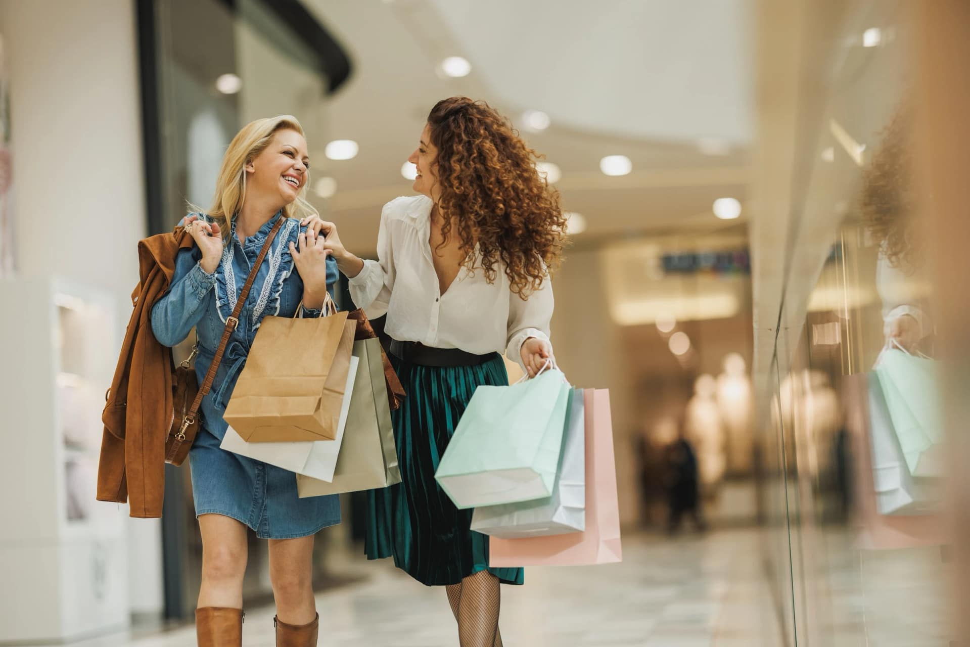 Two women smiling while shopping at mall