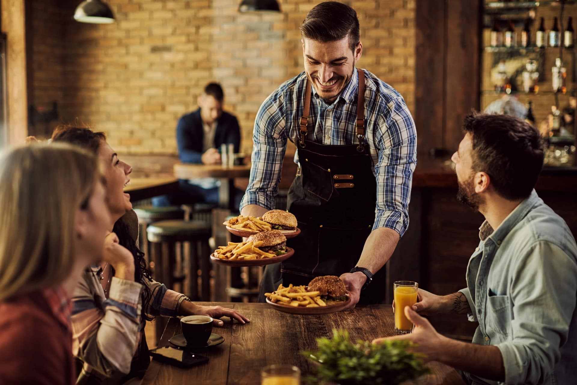 Waiter serving burgers and fries to happy customers