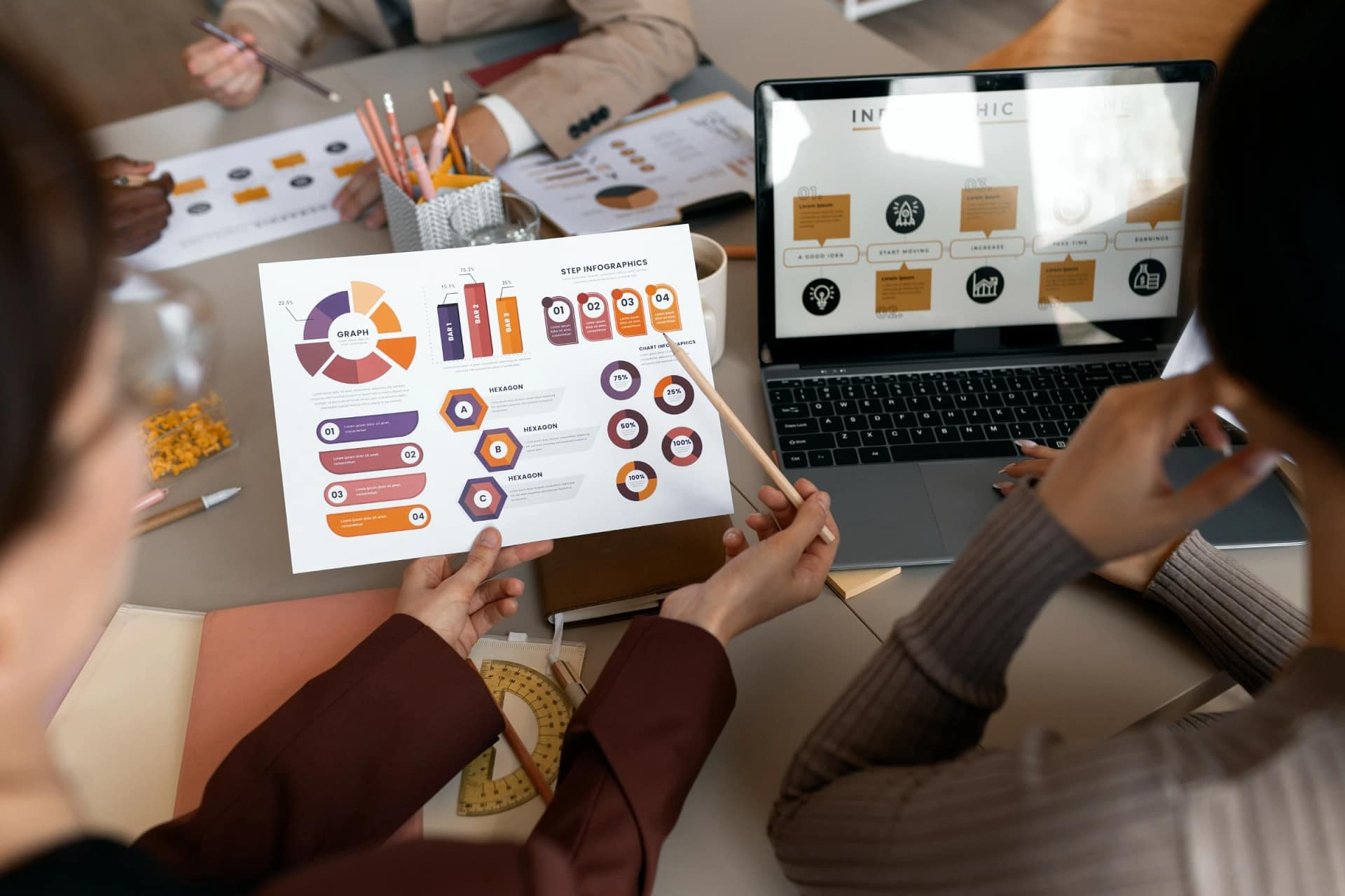 Team analyzing business infographics at meeting table