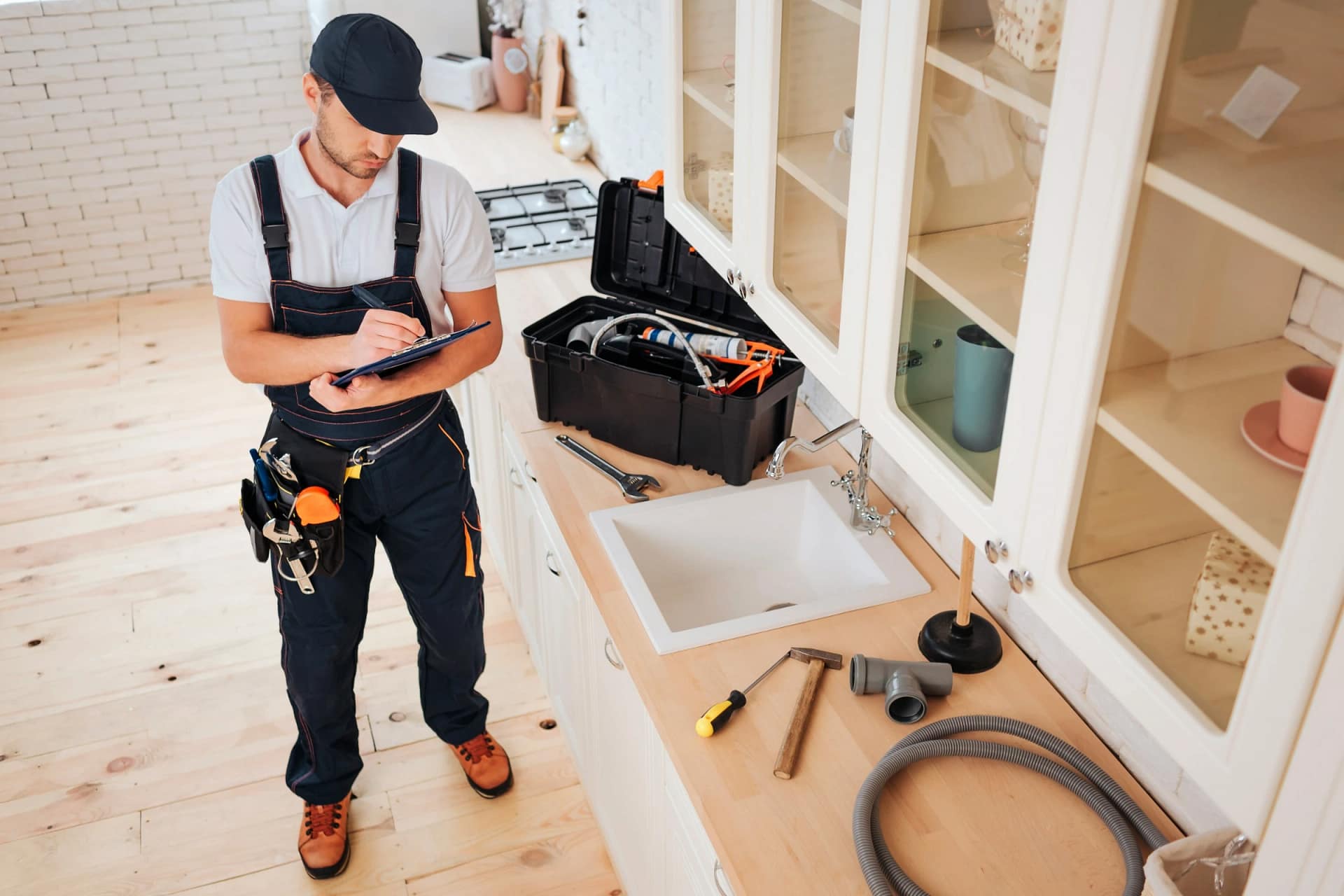 Plumber checking notes beside kitchen sink tools