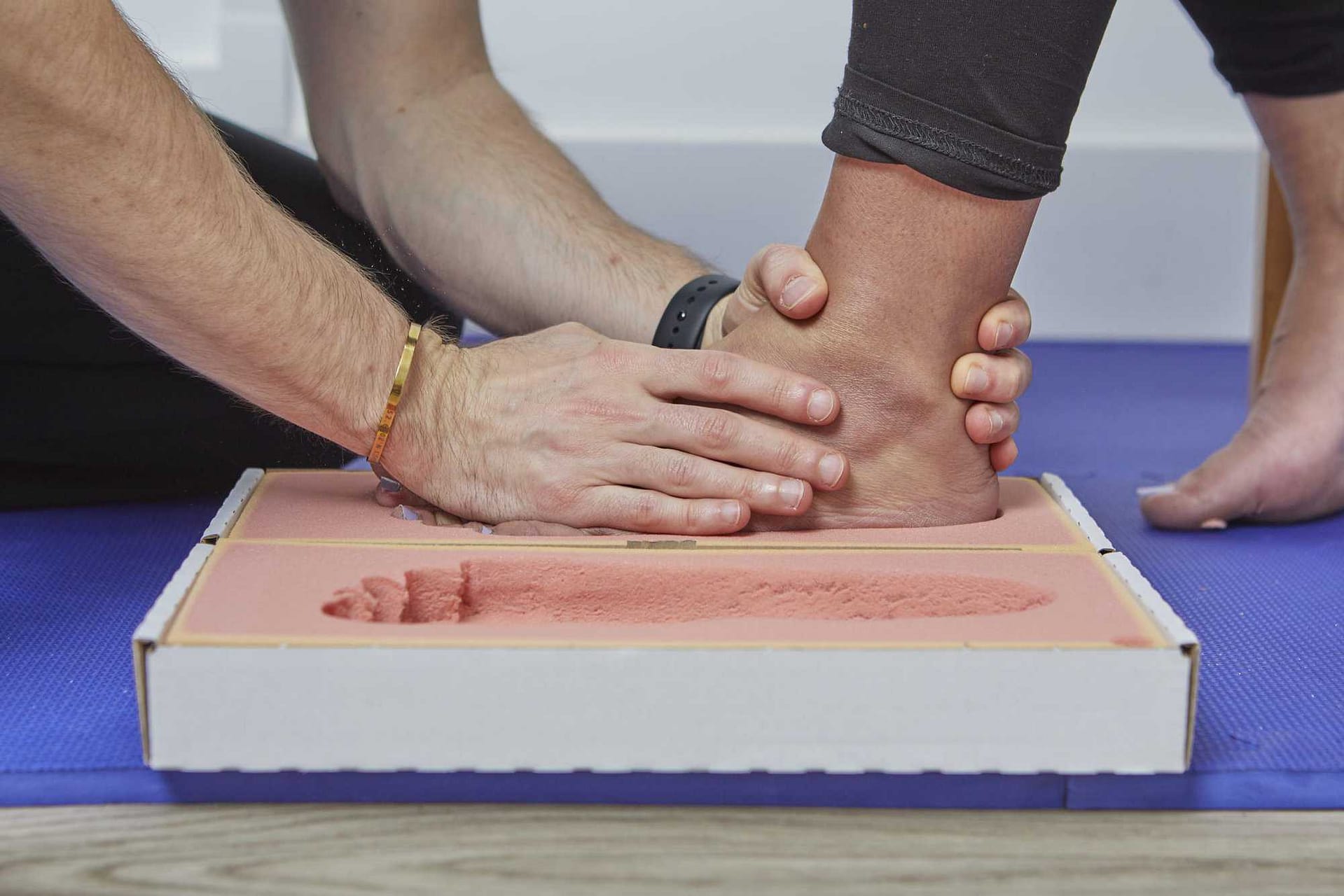 podiatrist placing patient's foot into foam impression box to take negative cast