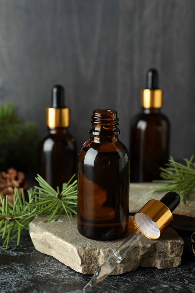 Aromatherapy concept with pine oil on black smoky table