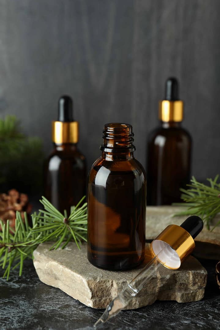 Aromatherapy concept with pine oil on black smoky table