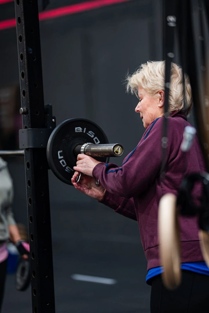 Older woman loading barbell in gym