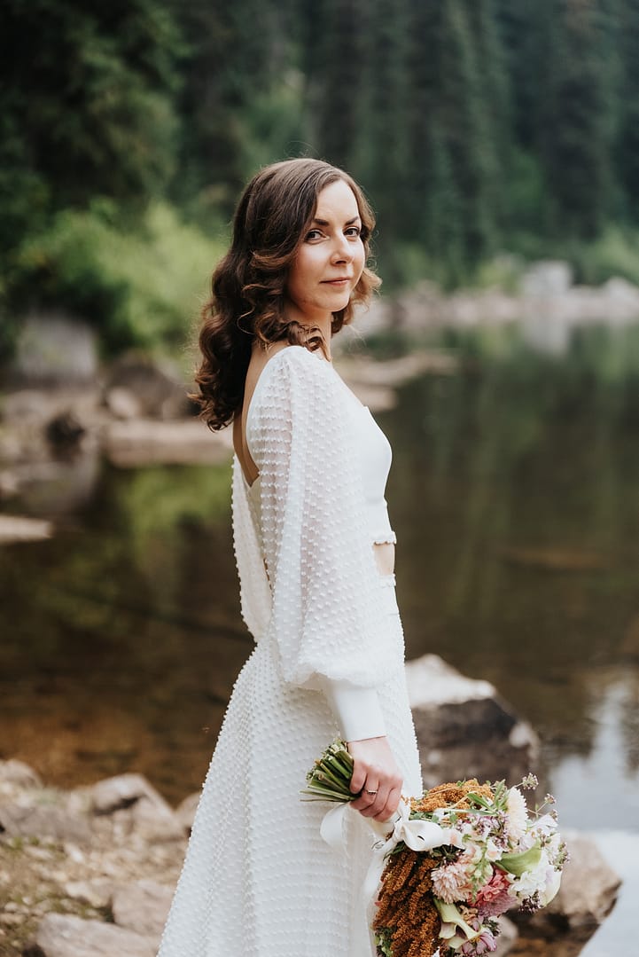 Bride with bouquet near forested lake Gibson.