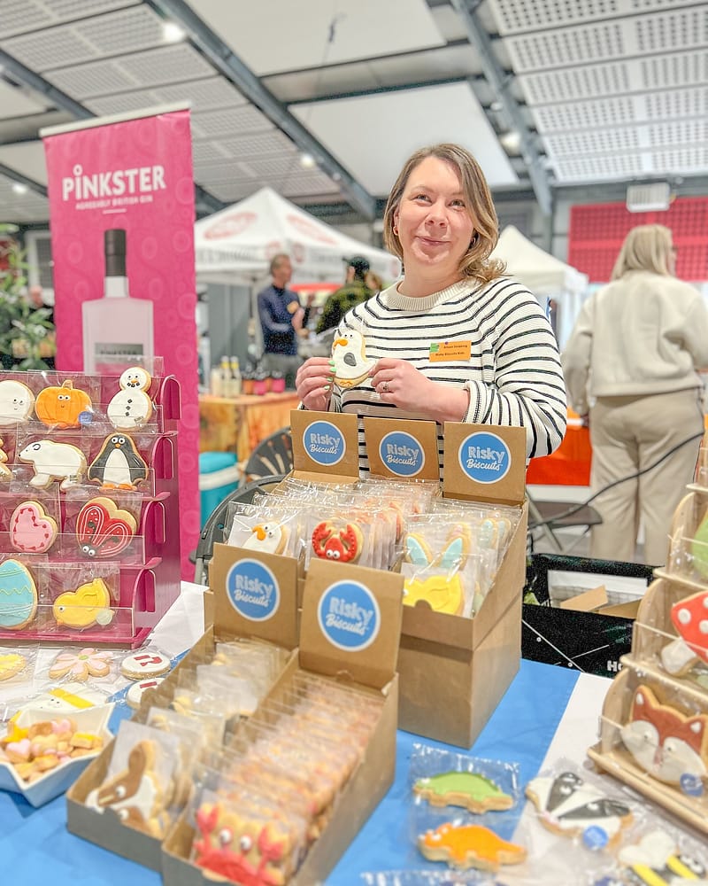 Woman showcasing decorated biscuits at a market stall.