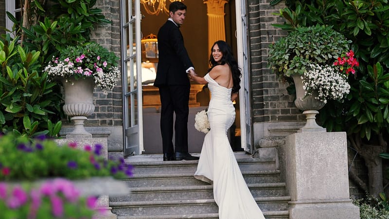 Bride and groom on elegant stone staircase.
