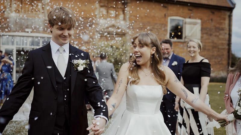 Joyful wedding couple walking through confetti shower.