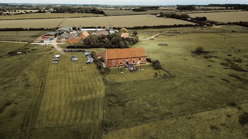 Aerial view of farm with parked cars and fields.