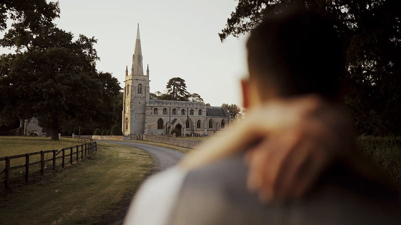 Couple embracing near old church at sunset.