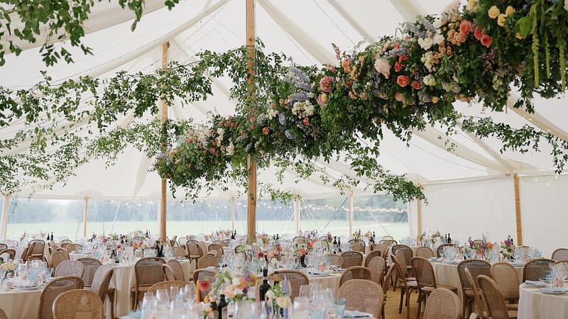 Elegant wedding marquee with floral arrangements and tables.