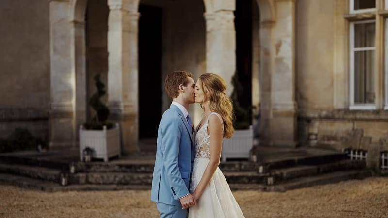 Bride and groom kiss in elegant setting.