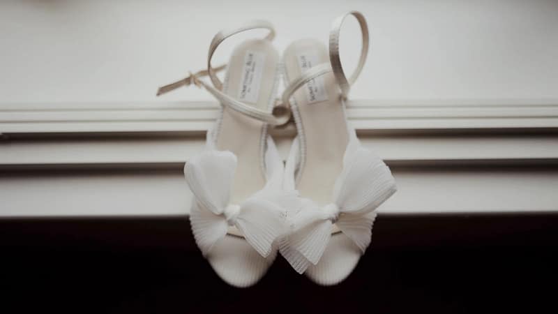 Elegant white sandals with bows on display.