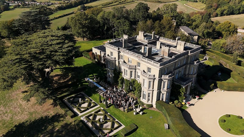 Aerial view of stately home and gardens, countryside surrounding.