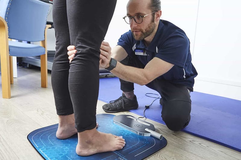 PODIATRIST EXAMINING KNEE OF PATIENT whilst standing