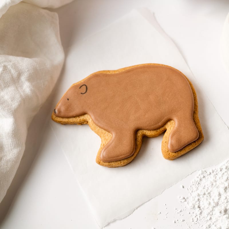 Bear-shaped cookie on parchment paper.