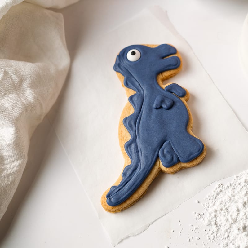 Blue dinosaur-shaped biscuit on white background.