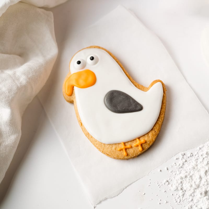 Seagull-shaped iced biscuit on parchment paper.