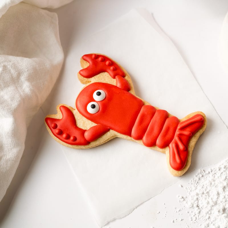 Red lobster-shaped iced biscuit on paper.