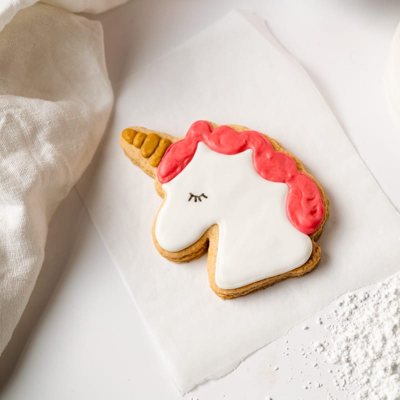 Unicorn-shaped biscuit with pink icing mane.