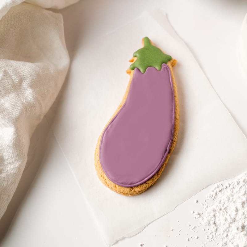 Aubergine-shaped iced biscuit on white background