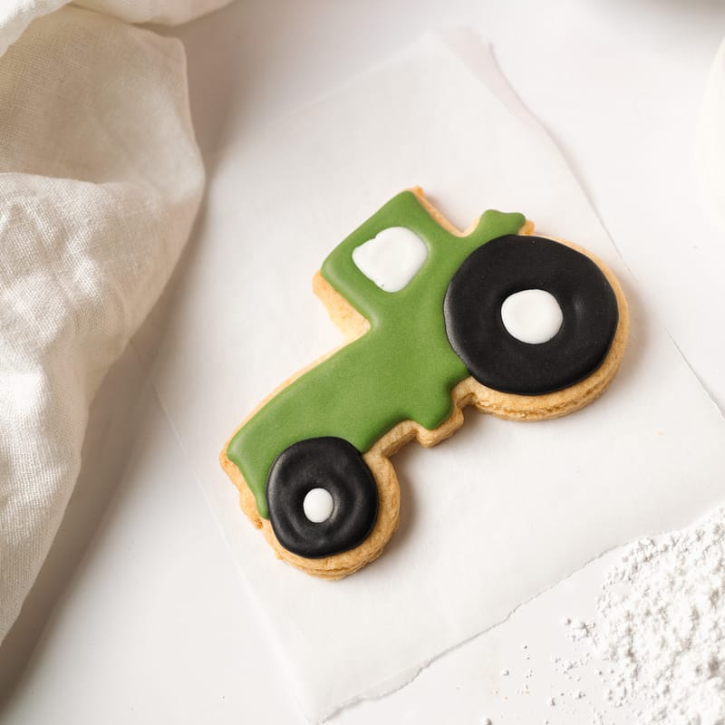 Green tractor-shaped cookie on white paper.