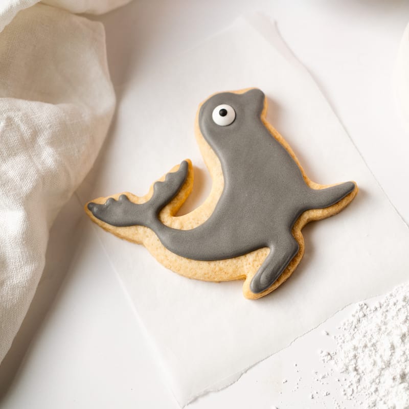 Seal-shaped biscuit with grey icing on parchment.